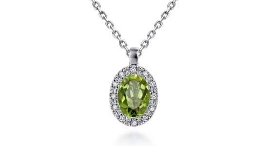 A peridot pendant necklace with an oval cut gem and a halo of diamonds in a silver setting