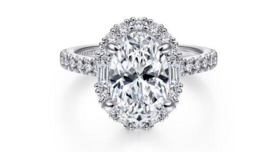 a white gold oval cut engagement ring in a halo setting fitted with both round and baguette cut diamonds
