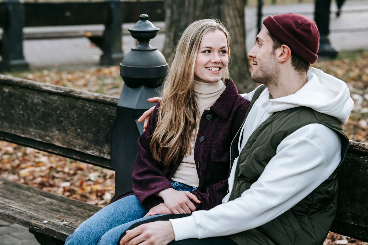 A smiling couple having a meaningful conversation on a park bench.