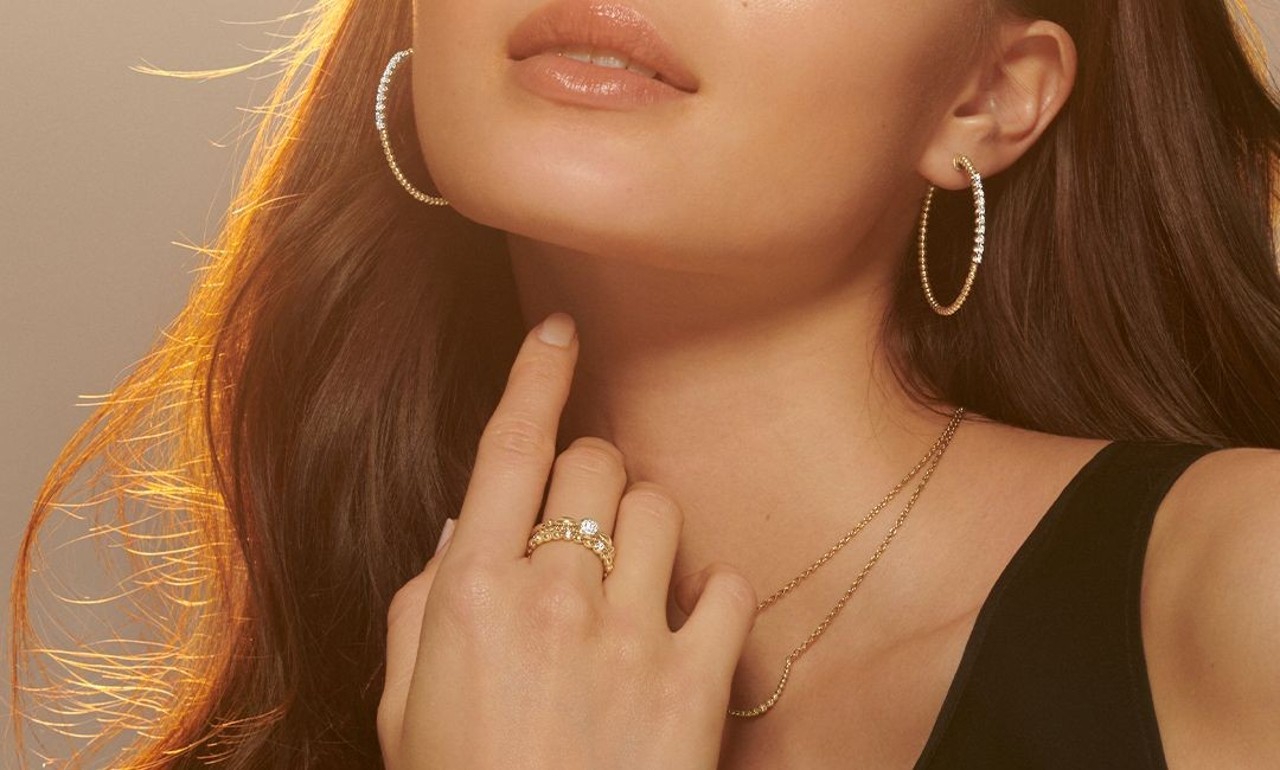 Woman wearing hoop earrings, a necklace, and an engagement ring by Gabriel & Co.