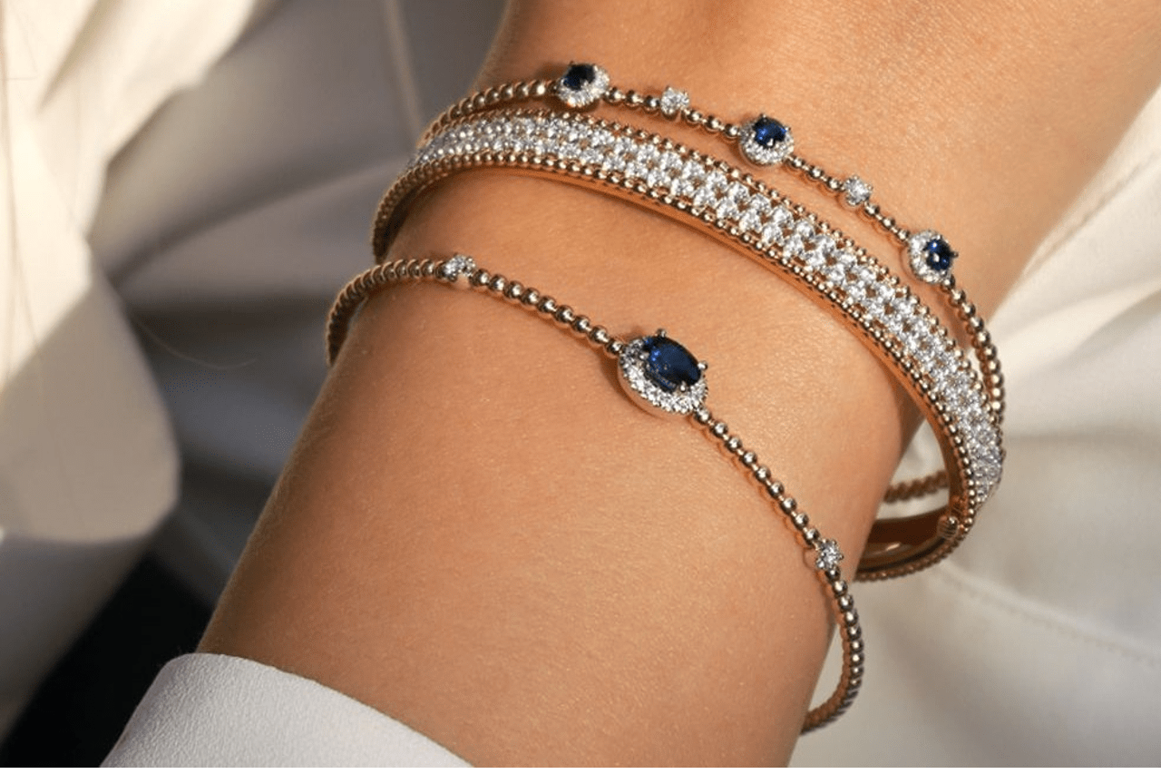 A woman wearing three diamond bracelets, two with sapphire details from Gabr