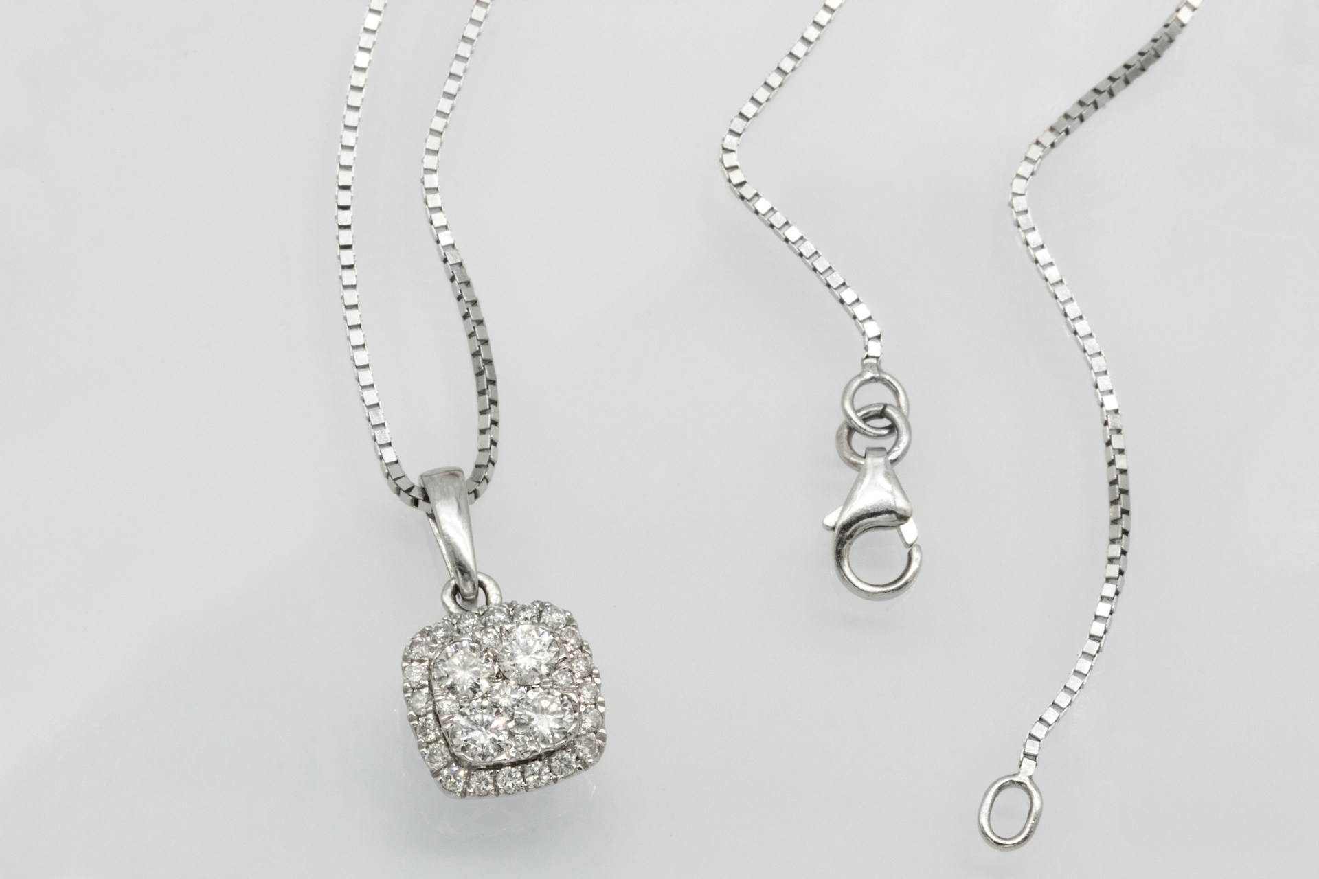a white gold diamond pendant necklace lying on a gray surface