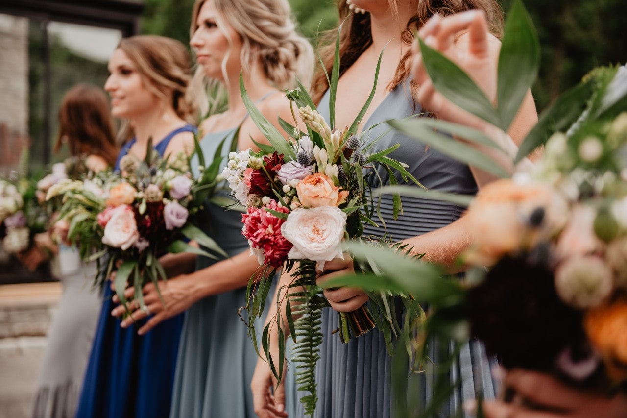 A close-up of gorgeous bouquets being held by bridesmaids, all wearing a different shade of blue.