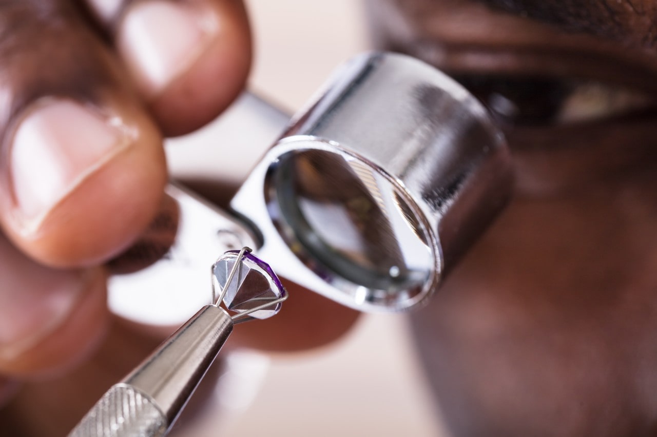 A gemologist inspects a loose diamond through a jeweler's loupe for clarity and precision.