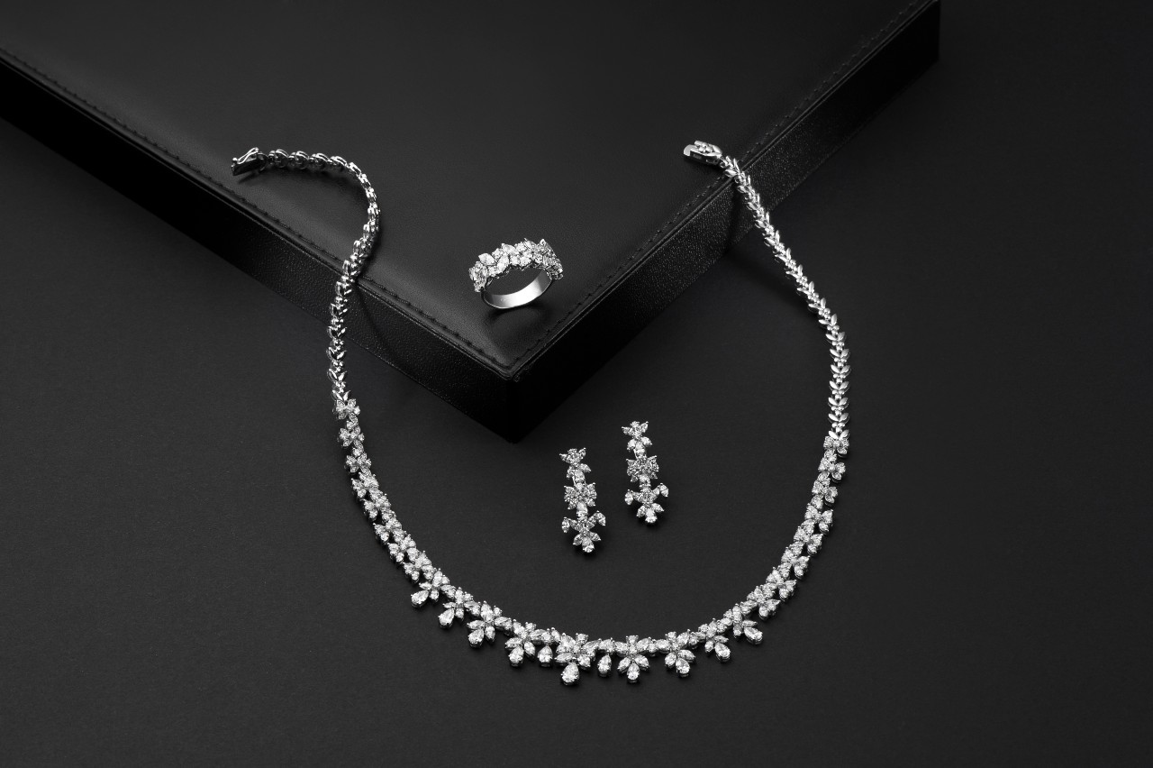 Elegant diamond jewelry set on black background, featuring a sparkling necklace, matching earrings, and a ring.